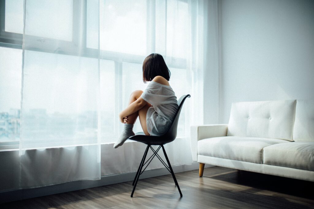 Mujer sentada sobre una silla mirando una ventana